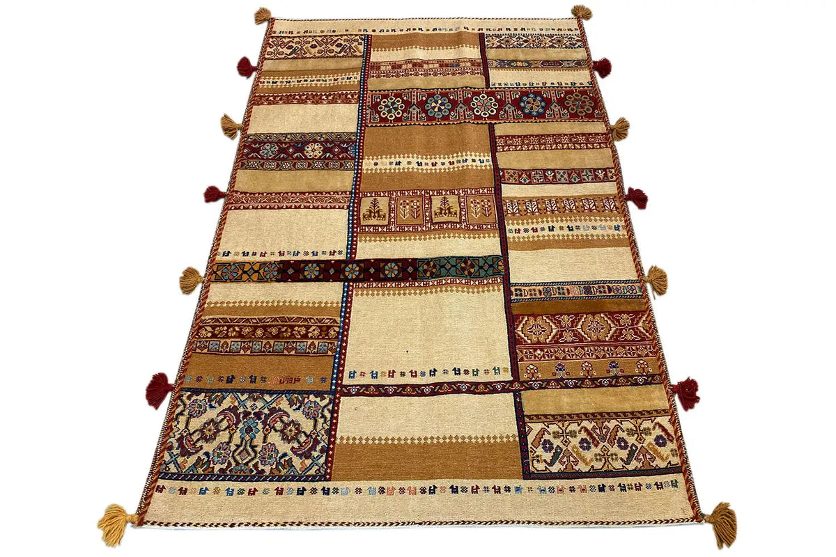 Rug viewed from above: patchwork stripes in beige, brown, red, and blue, tassels.