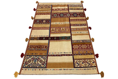Rug viewed from above: patchwork stripes in beige, brown, red, and blue, tassels.