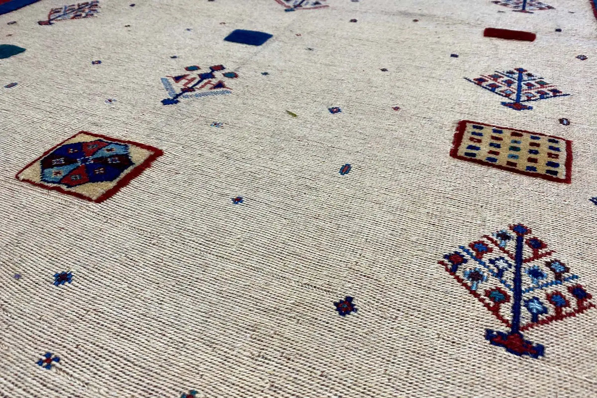 Detailed view of the patterns: beige fabric with blue and red designs