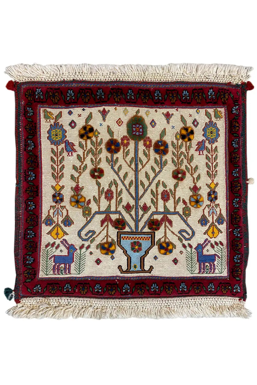 Decorative cushion cover with an all-over pattern, red trim, and tassels on the sides