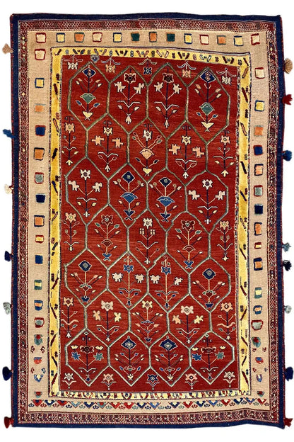 Reddish-brown oriental rug with a red medallion pattern, blue border, and tassels
