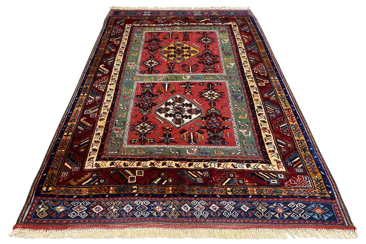 Triangular oriental rug with red pattern, ornamental border and fringes