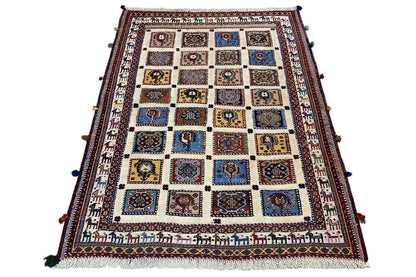 Rug in the still image: beige pile with blue-red tiles and a wide patterned border