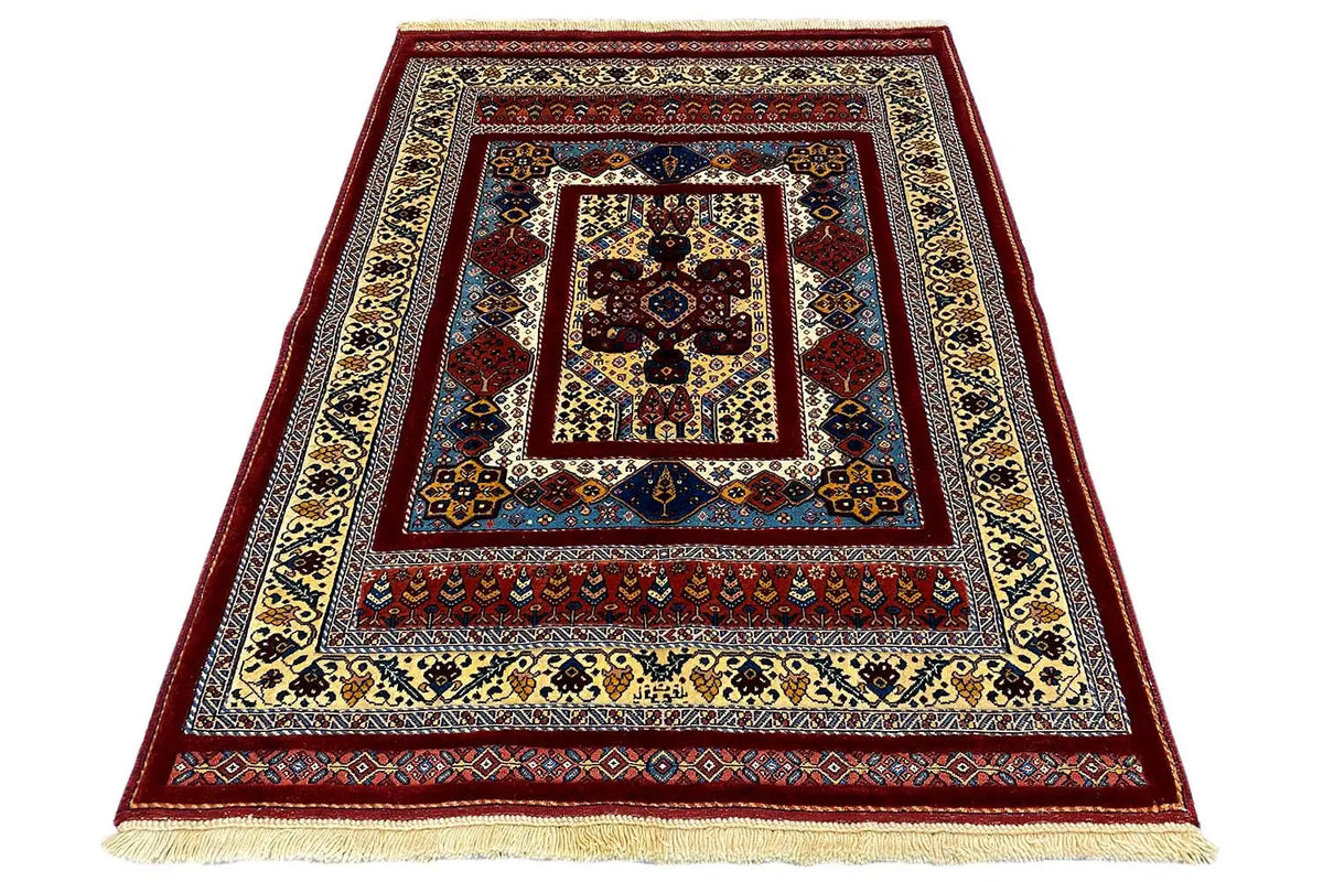 Rug viewed at an angle with a dark red border, blue center, and beige fringes