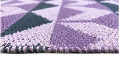 Flatweave rug with fringed edge and purple geometric pattern, close-up view
