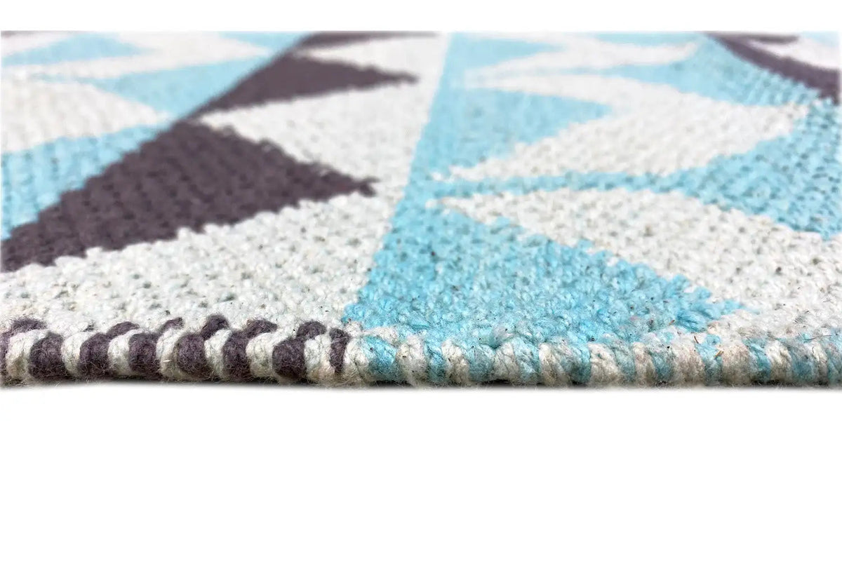 Kilim rug with a turquoise, white, and brown geometric pattern; close-up of the edge fringe