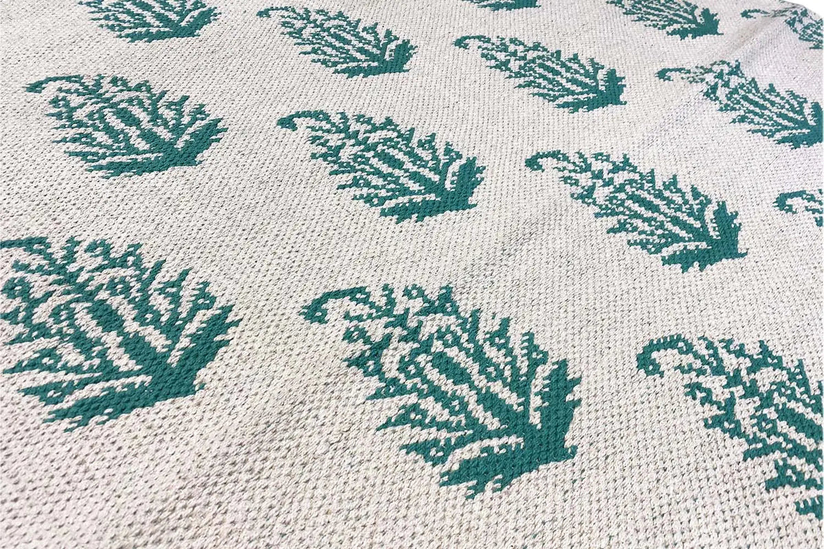 Flatweave rug with a light background and green leaf patterns in a textured weave