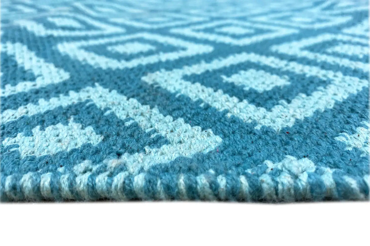 Modern kilim rug detail: blue texture, diamond pattern, and fringes