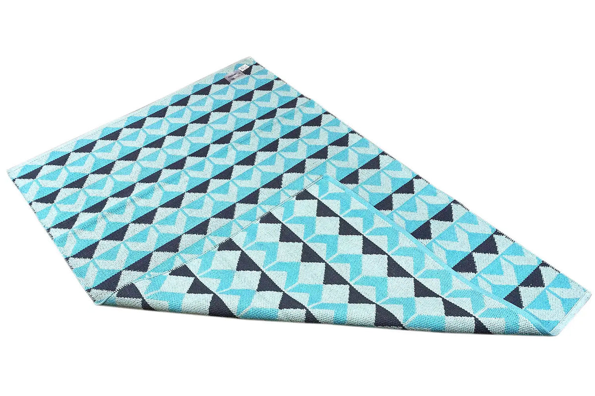Tufted rug in turquoise and white with dark zigzag triangles; folded view
