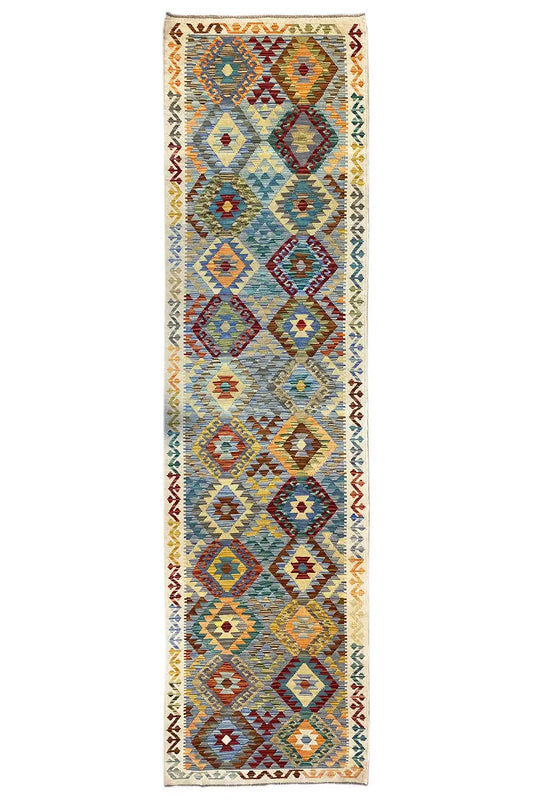Rectangular kilim runner with diamond and zigzag patterns in blue, red, and yellow on a light background.