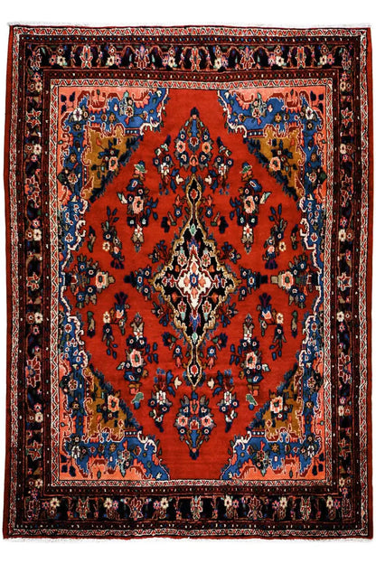 Oriental rug with a red central field, blue medallion, and finely patterned border