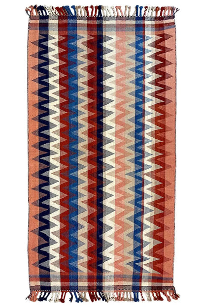 Rectangular rug with a geometric zigzag pattern in brown, blue, red, and beige, with fringes
