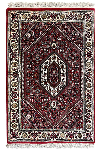Rectangular rug, red medallion pattern, cream borders, fringes along the edges