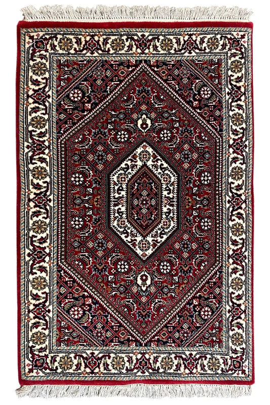 Rectangular rug, red medallion pattern, cream borders, fringes along the edges