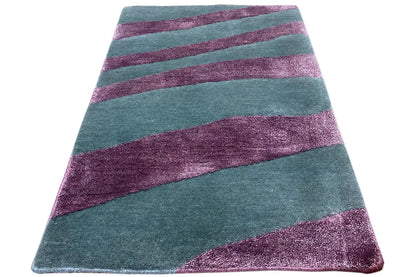 Rectangular rug with diagonally placed petrol-green and purple stripes
