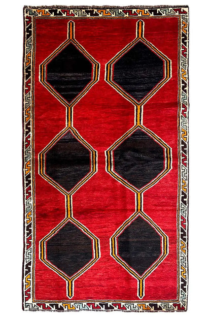 Red lori rug with stacked hexagons in black, gold-colored line border