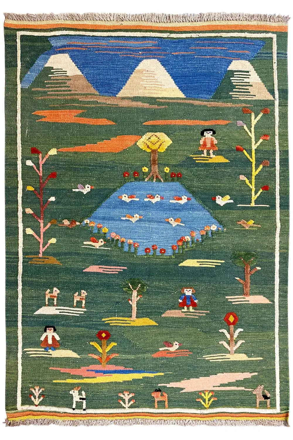 Green kilim rug with figures, trees, and mountains, a surrounding border and fringes