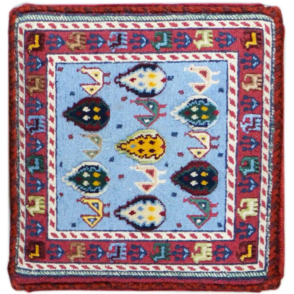 Carpet cube with a blue central motif, colorful ornamental insets, and a red border