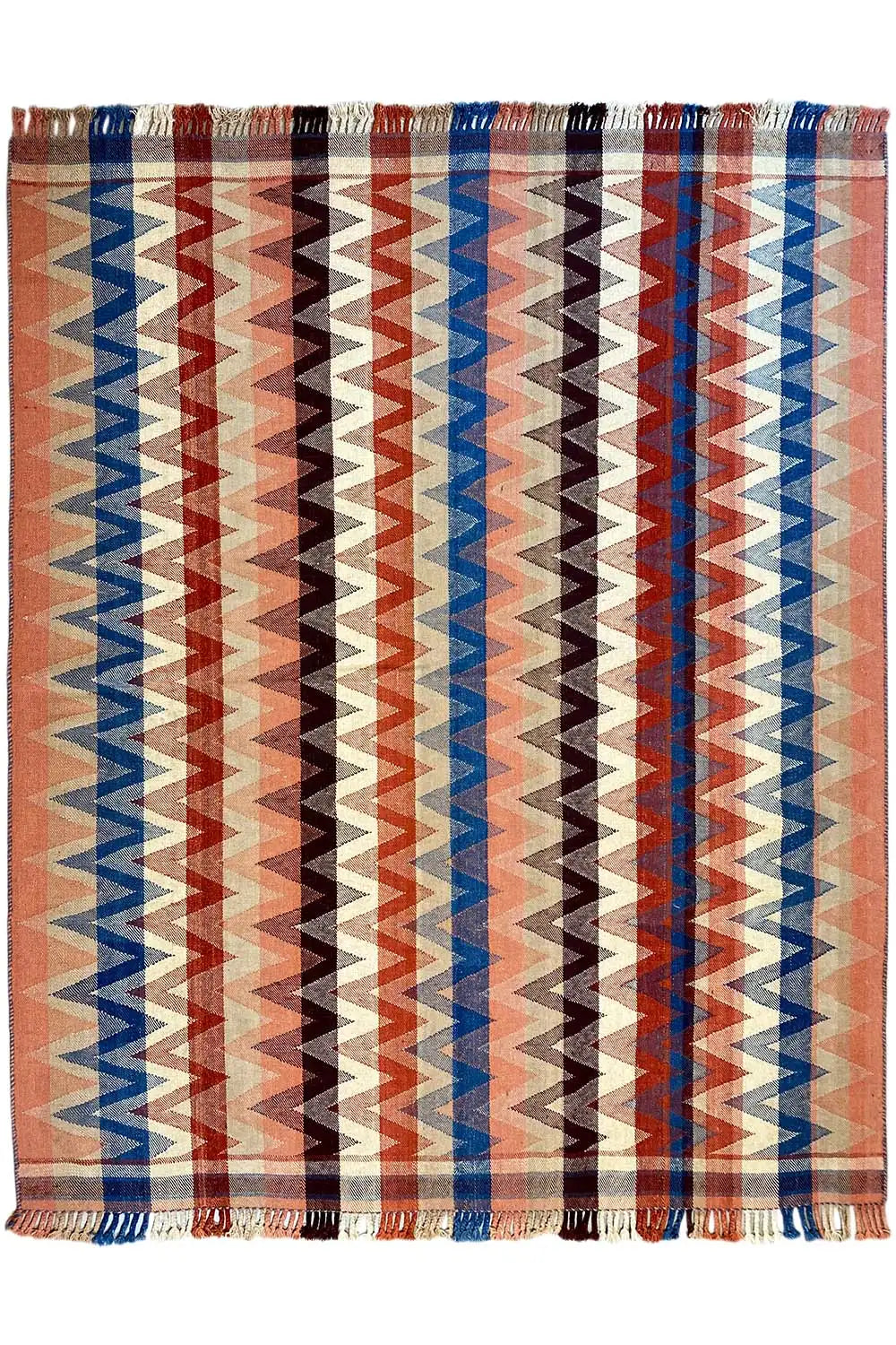 Rug with a rectangular zigzag design in rust, blue, and beige, with fringes