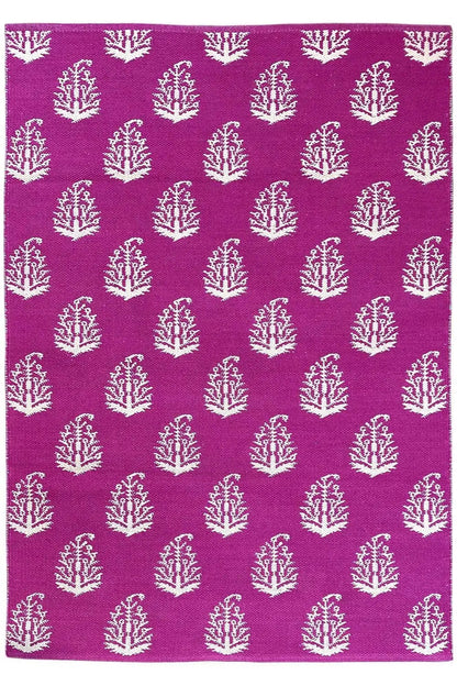 Modern flat-weave rug with purple fabric and white tree ornaments, flat lay