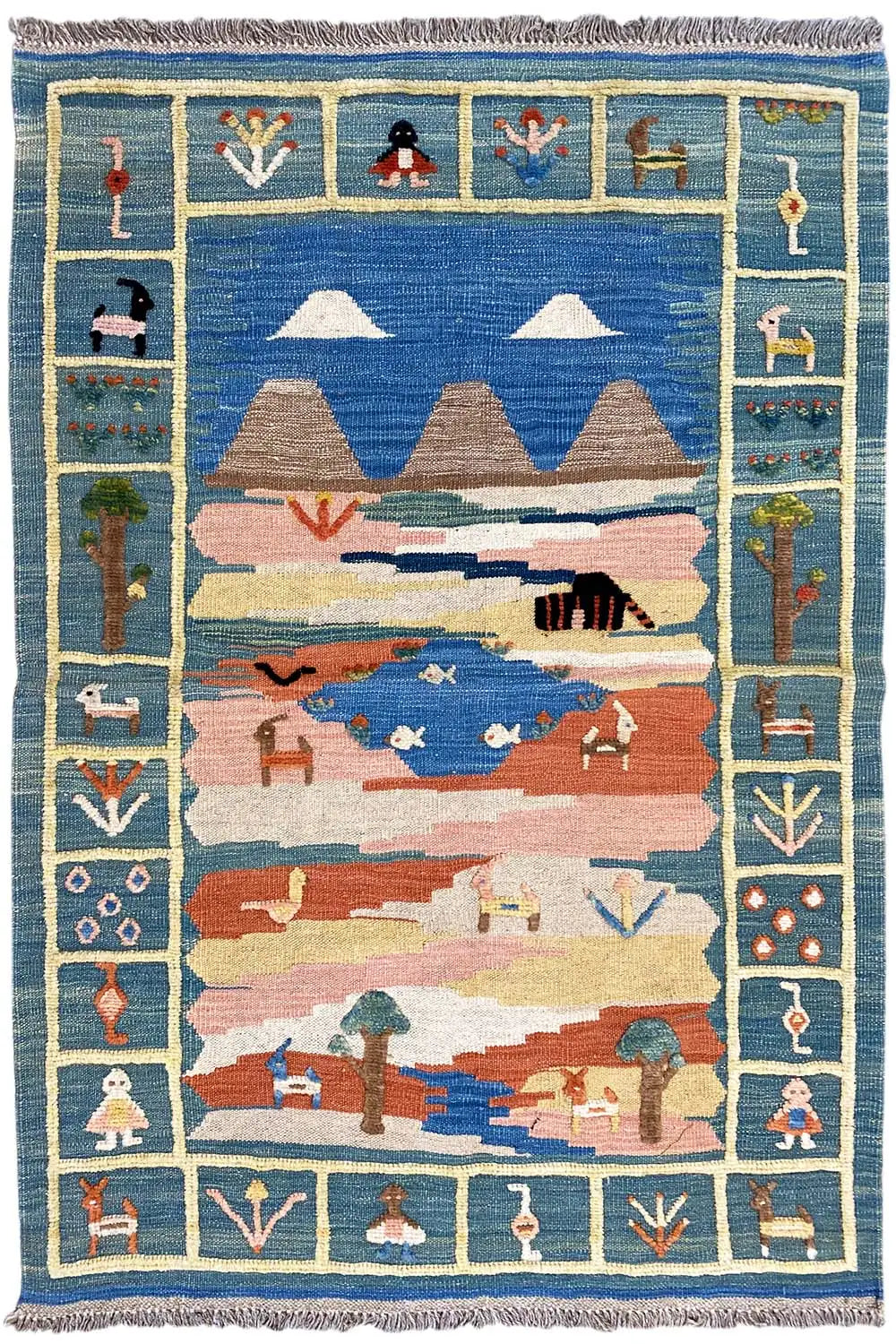 Kilim rug front view: blue field, mountains and animals in pastel colors, with fringes
