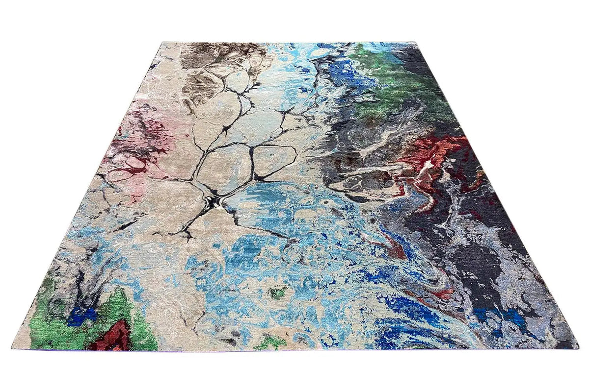 Rectangular designer rug with abstract color blocks in blue, beige, red, and green.