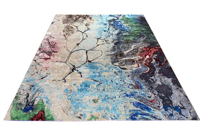 Rectangular designer rug with abstract color blocks in blue, beige, red, and green.