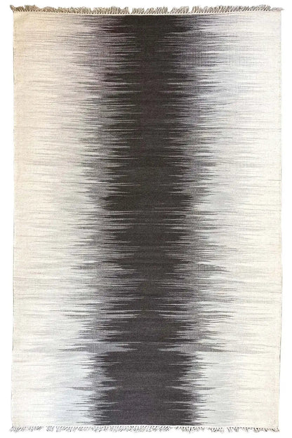 Rectangular gray kilim rug with dark gradient patterns and fringes along the edge
