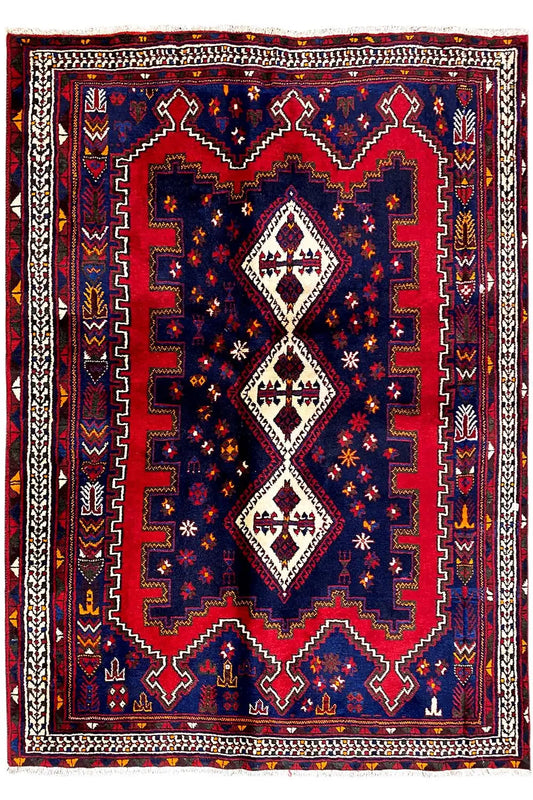 Rectangular Oriental rug with a dark blue pattern, red borders, and white diamonds.