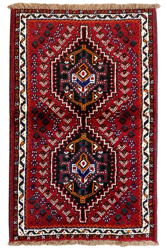 Rectangular oriental rug: red field, central medallions, fringes at the top and bottom