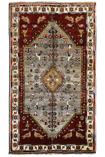 Gabbeh rug with a red and gray medallion and animal/symbol motifs, surrounded by a border