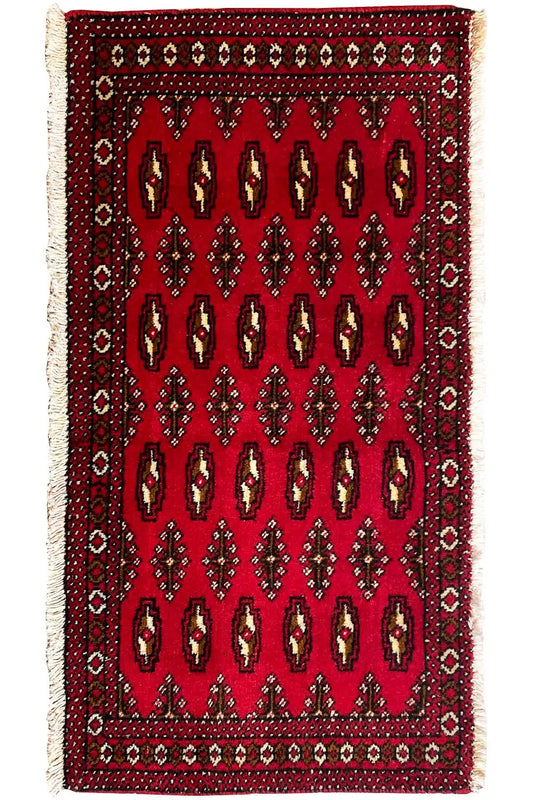 Compact red Turkmen carpet with vertical rows of ornaments and a dark border