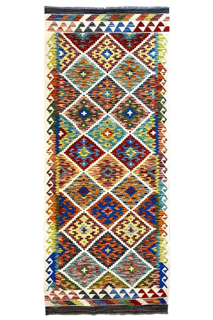 Afghan runner with a geometric pattern in blue, red, green, and yellow, with fringes