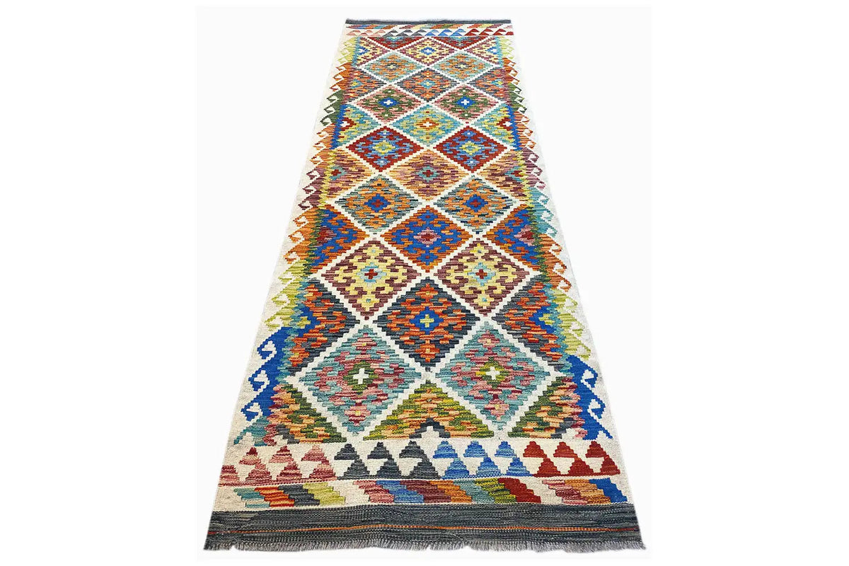 Multicolored Afghan runner with diamond and cross pattern, light background, and fringes