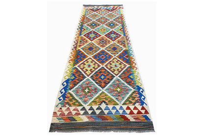 Multicolored Afghan runner with diamond and cross pattern, light background, and fringes