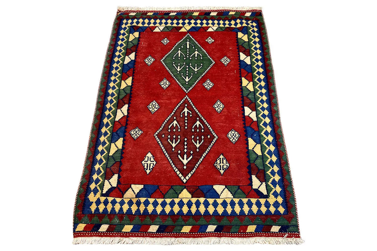 Multicolor kilim rug in a standing view: red field with diamonds and ornaments, fringes at the bottom