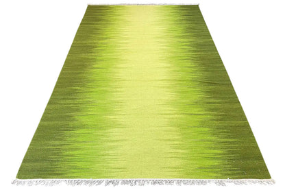 Green kilim rug in angled view with fringes along the bottom edge