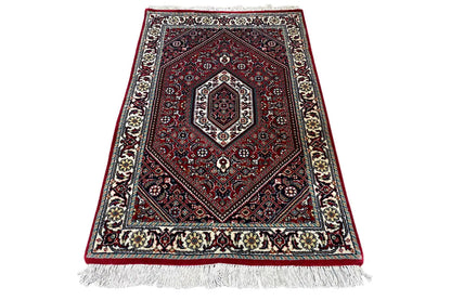 Rug (92x60 cm), red and blue, with a rectangular medallion, dark background, fringes