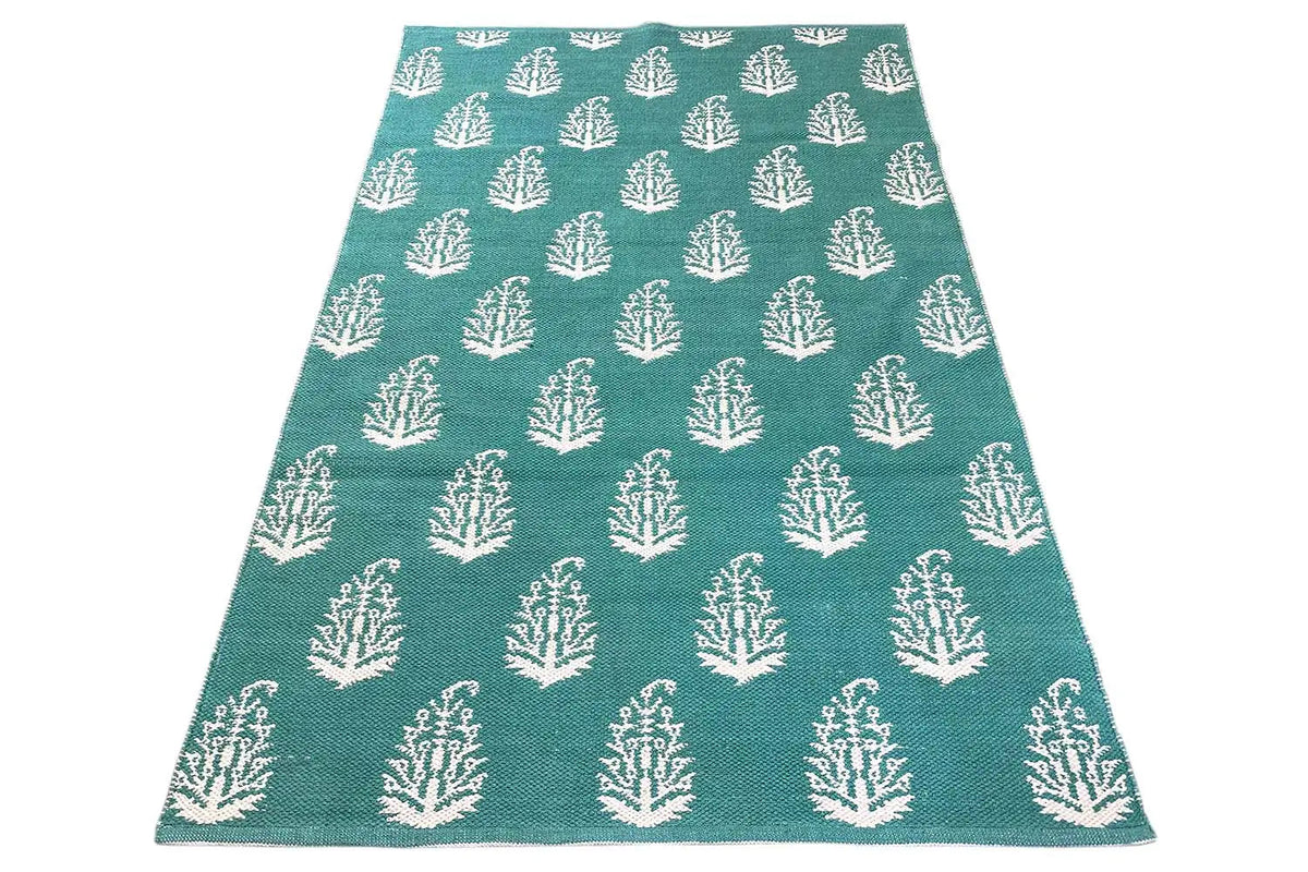 Modern green kilim rug with a white tree pattern, viewed from above