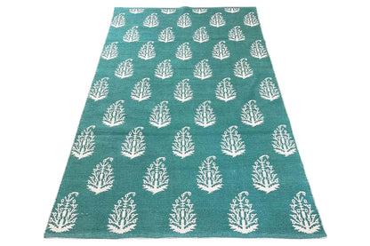 Modern green kilim rug with a white tree pattern, viewed from above