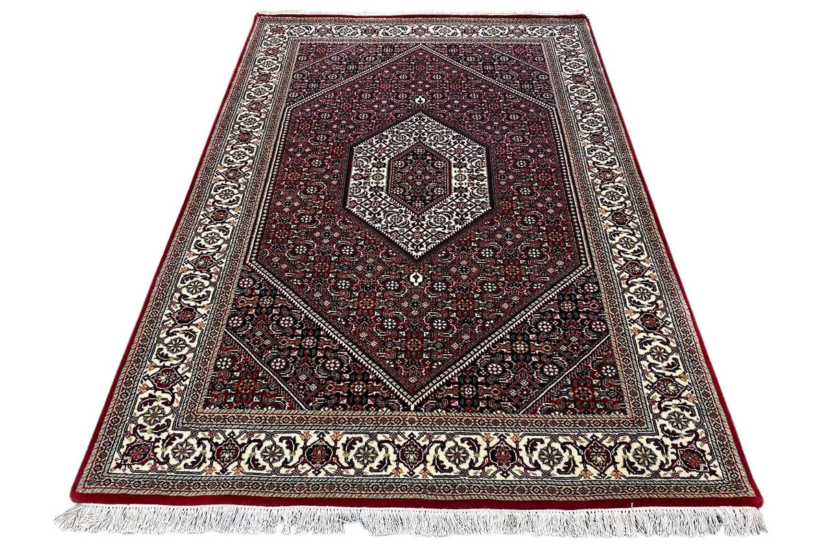 Bidjar rug folded/diagonally with fringes at the edge and a red patterned center