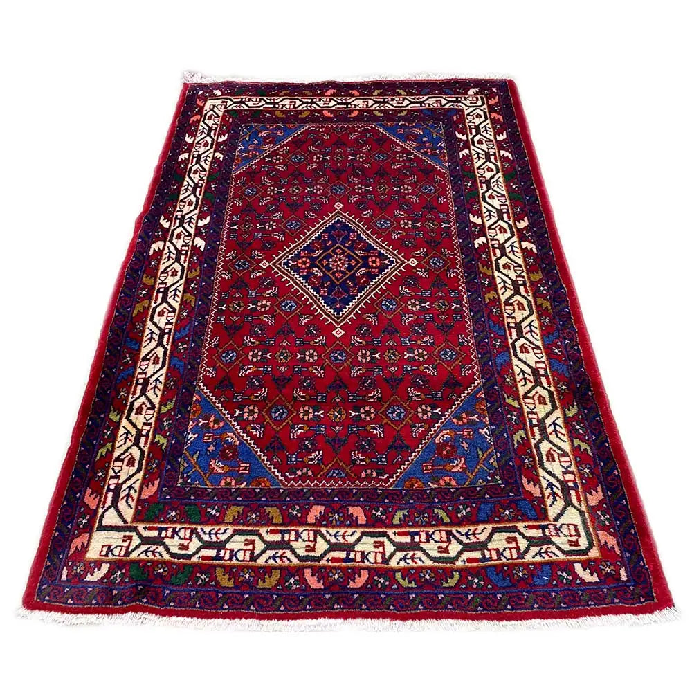 Rectangular Oriental rug with a dark red background, blue central medallion, and decorative border