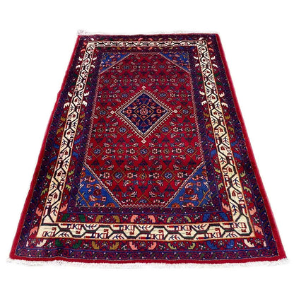 Rectangular Oriental rug with a dark red background, blue central medallion, and decorative border