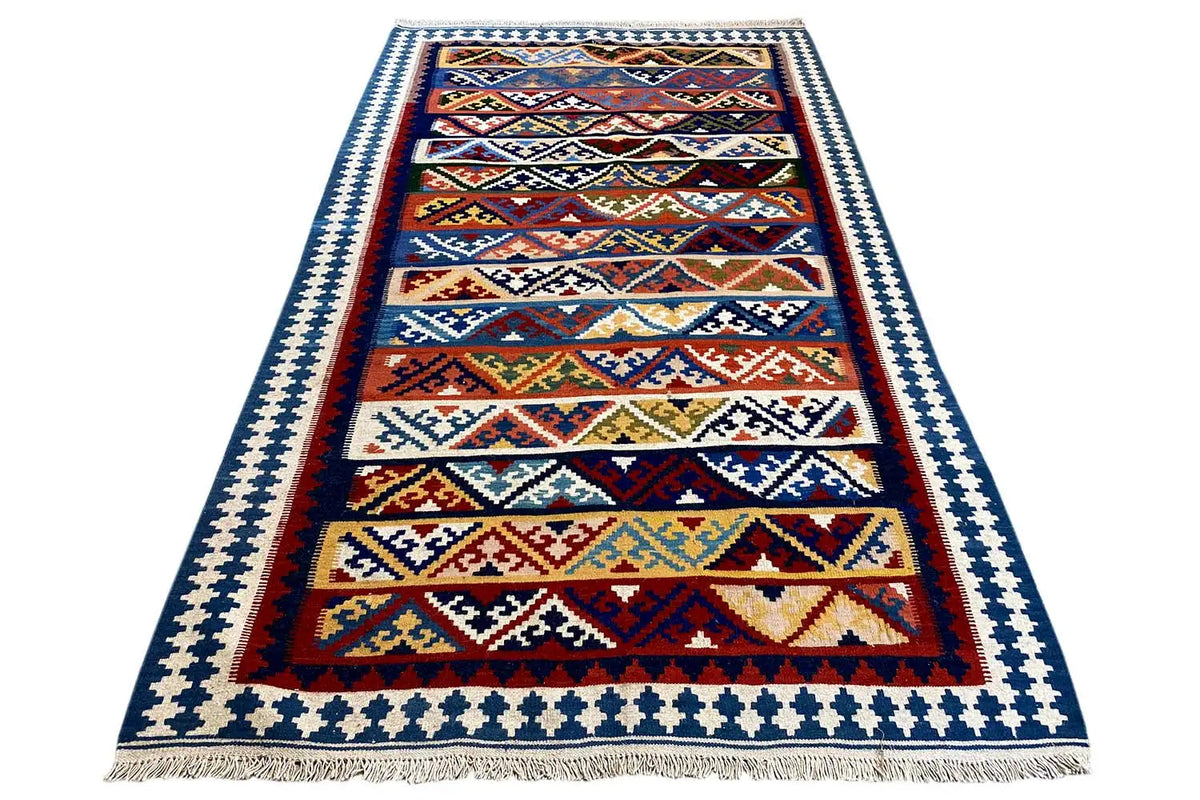 Kilim rug with borders and a linear pattern, fringes at the bottom, multicolored central design.