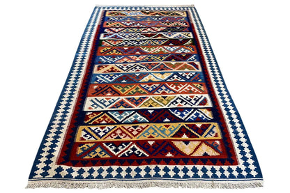 Kilim rug with borders and a linear pattern, fringes at the bottom, multicolored central design.