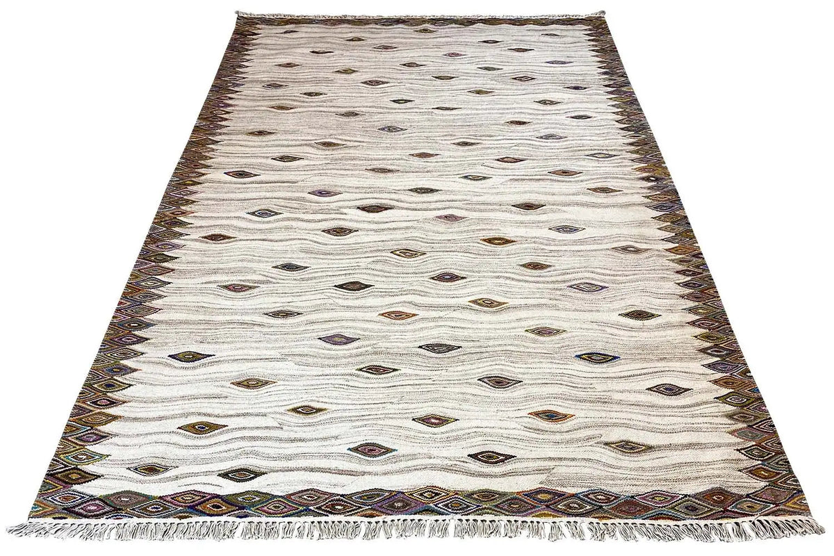 Cream-colored kilim dhurrie rug with diamonds and a dark brown decorative border, angled view