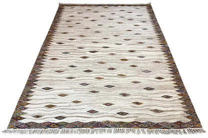 Cream-colored kilim dhurrie rug with diamonds and a dark brown decorative border, angled view