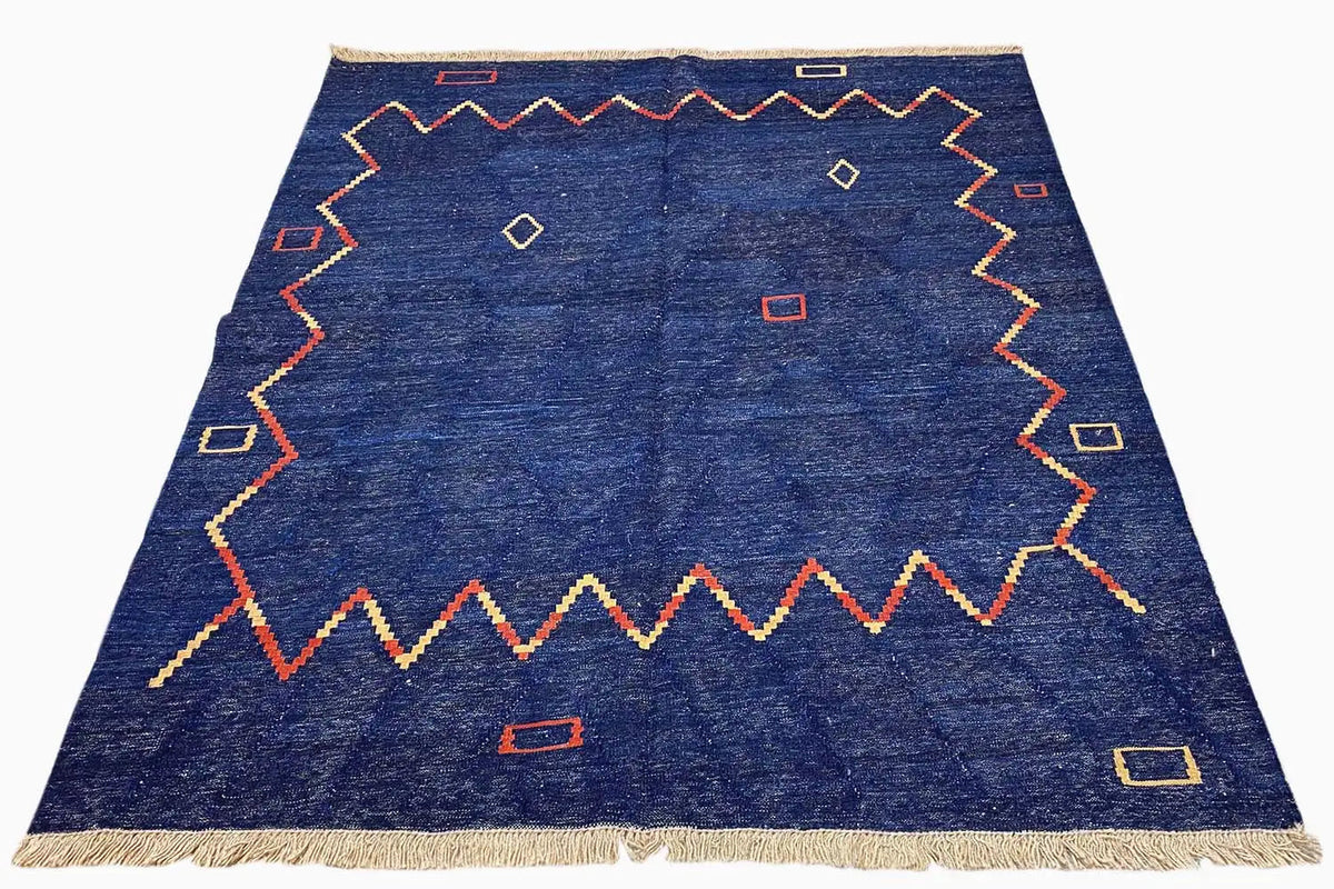 Qashqai kilim rug in oblique view, blue with a border pattern and fringes