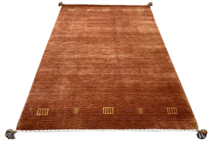 View of a brown woven rug with gold ornaments and fringe along the edge