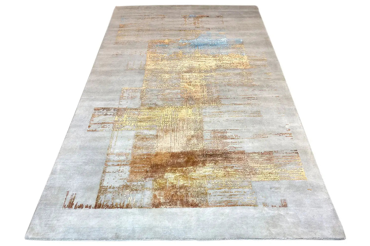 Designer rug with an abstract patchwork pattern in light gray, beige, gold, and blue